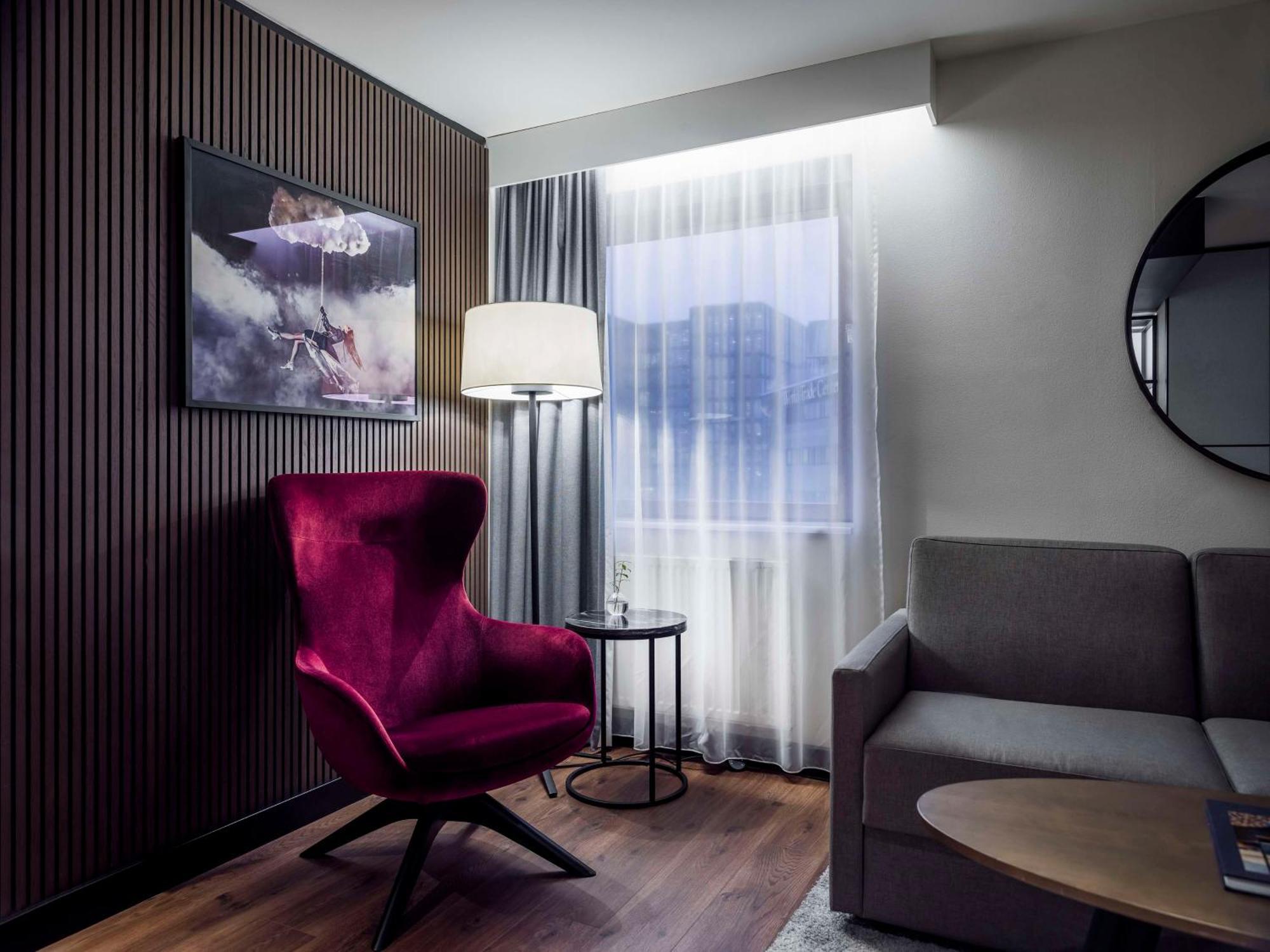 Radisson Blu Royal Viking Hotel, Stockholm Ngoại thất bức ảnh The photo shows a cozy and modern living area. On the left, there's a striking purple armchair with a unique design, accompanied by a round side table. Next to the chair, a floor lamp provides soft lighting. To the right, there's a gray sofa, creatin